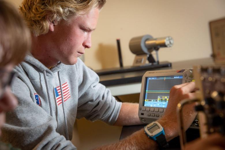 Male Physics student studying data on a monitor.