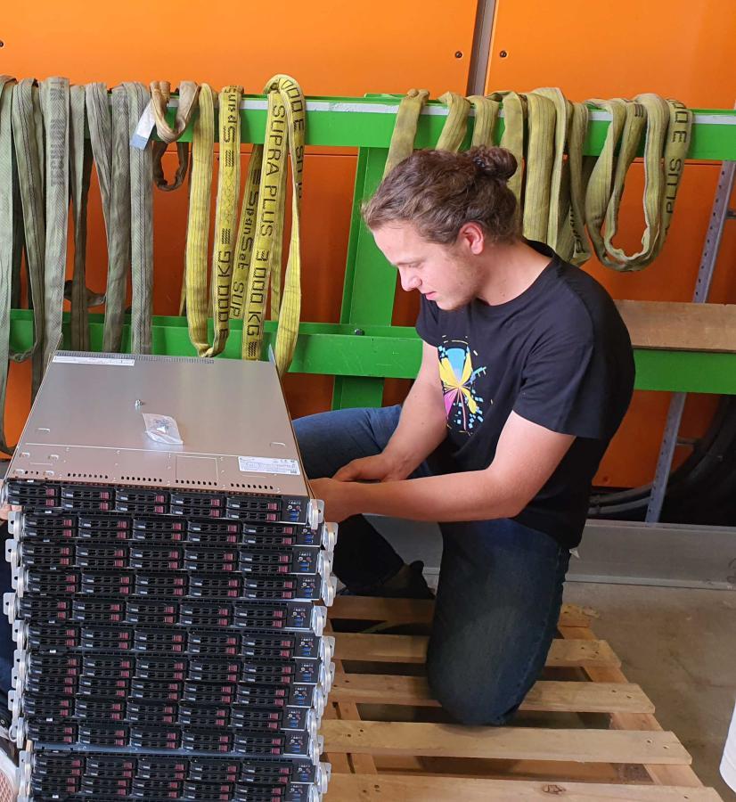 Chandler Baker '24 unpacks servers at CERN to create a large computing farm of about 50,000 processing applications that the software-based High Level Trigger uses to analyze new data from ATLAS Experiment at CERN. 